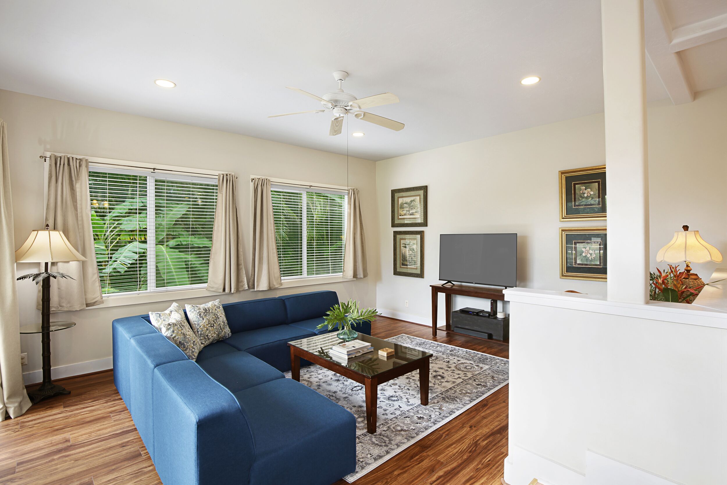 A living room with a blue sofa, a coffee table, a TV, and framed pictures on the wall.