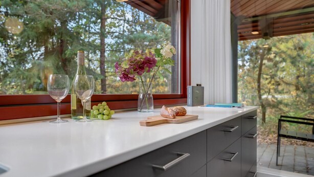 A kitchen counter with wine glasses, a bottle, grapes, flowers, and a wooden board with a pastry. - Awesome home in Grenaa with WiFi (Grenaa)