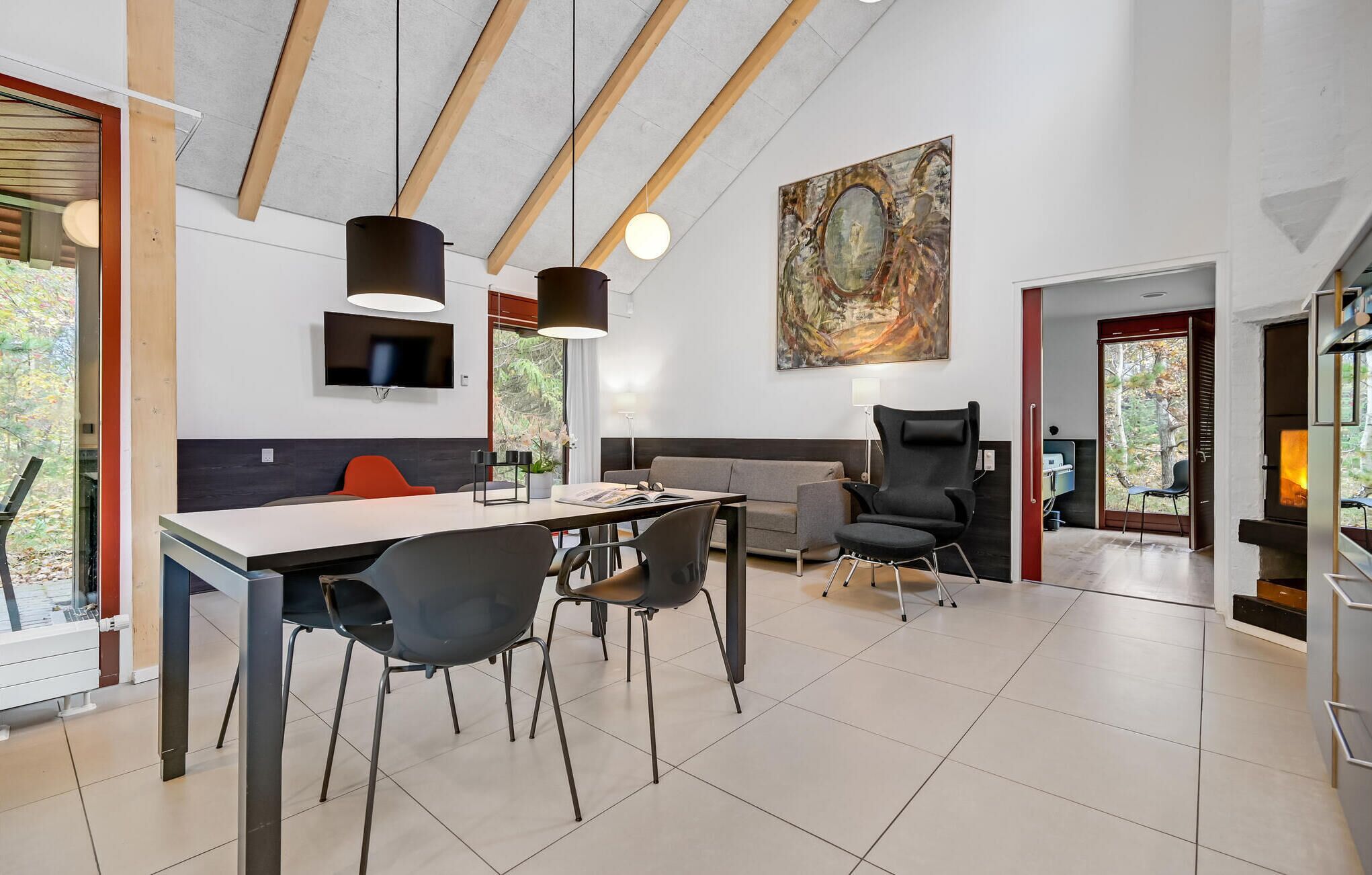 A modern interior with a dining area, seating, a fireplace, and a large abstract painting.