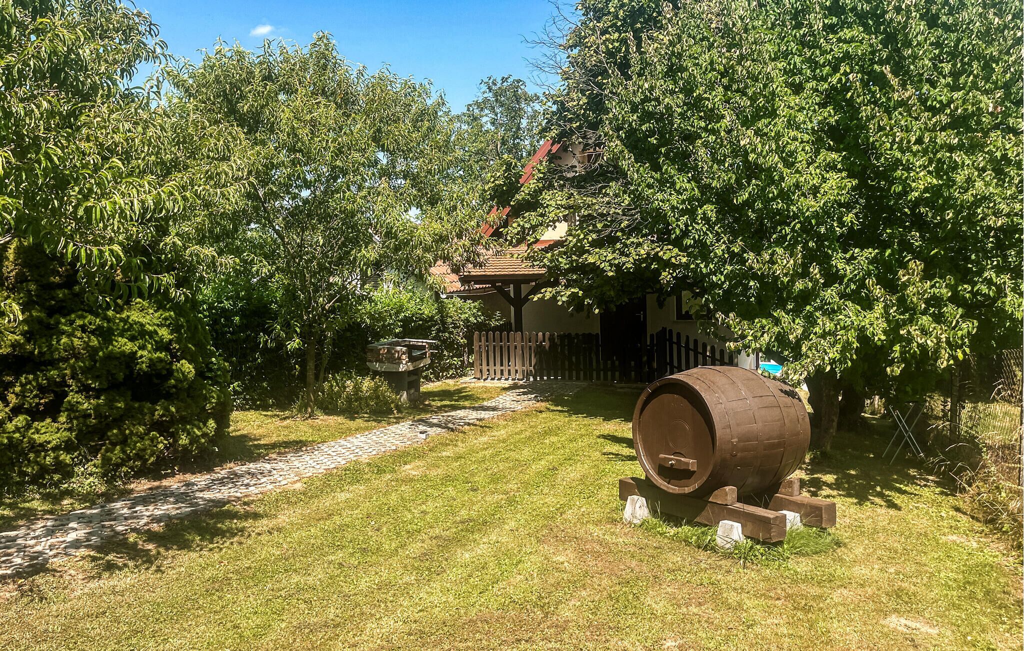A rustic outdoor setting with a wooden barrel, a stone pathway, and a wooden fence.
