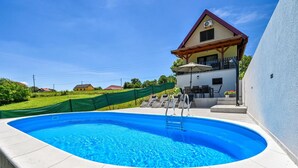 A swimming pool with a ladder, outdoor seating, and a house in the background. - Stunning home in Seketin (Seketin)