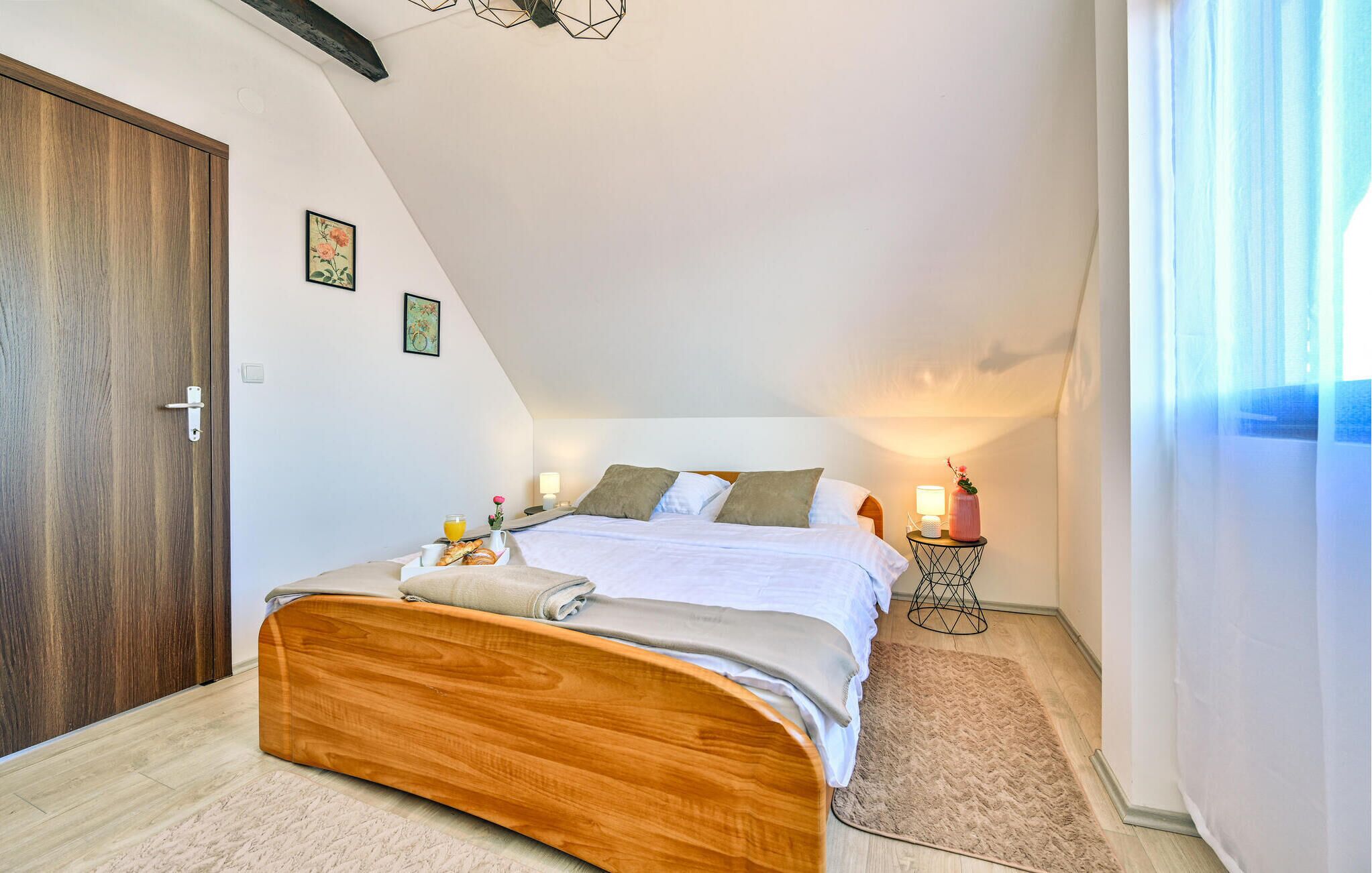 Een slaapkamer met een houten bed, een nachtkastje met een lamp en een raam met gordijnen.