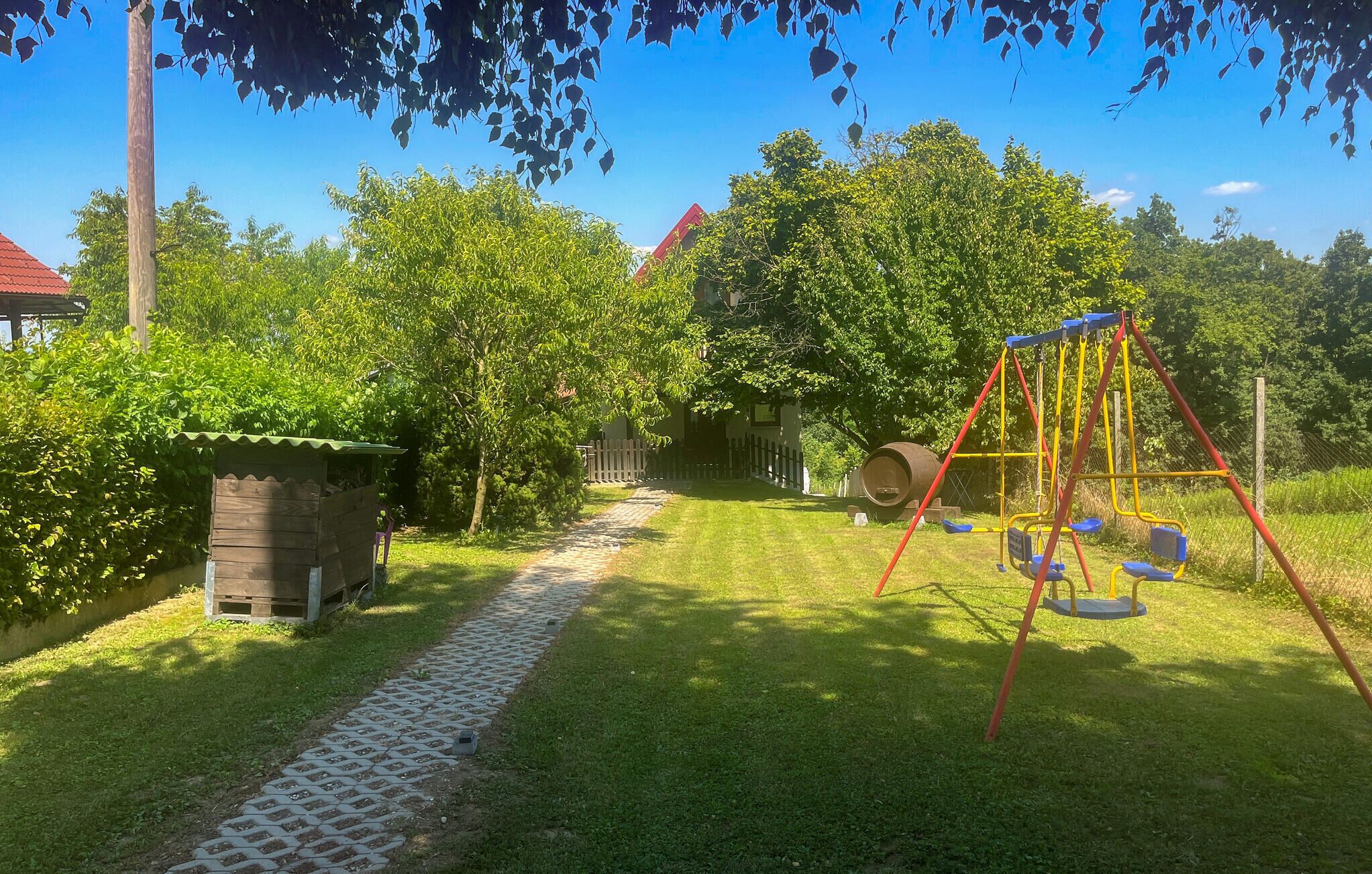 Un jardín con un columpio, una estructura de madera y un sendero pavimentado.