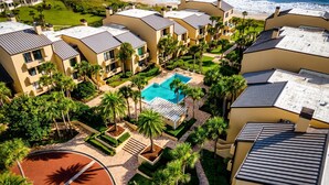A resort with multiple buildings, a swimming pool, and a beach view.