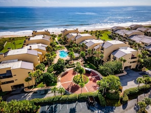 Ein Resort mit mehreren Gebäuden, einem zentralen Pool und Blick auf den Strand.