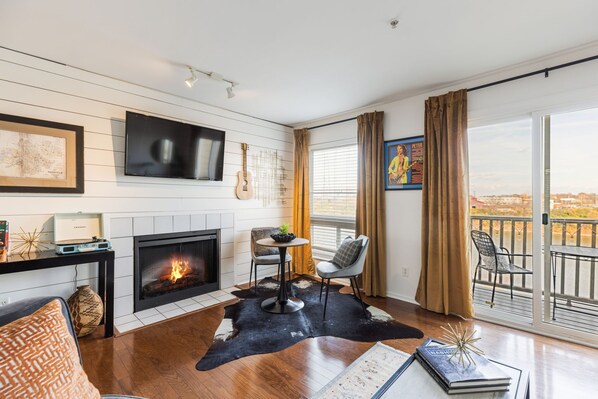 Ein modernes Wohnzimmer mit Kamin, Fernseher und einem Balkon mit Blick.
