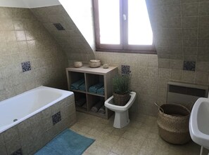 Tina con regadera, bidet, jabón, papel de baño 