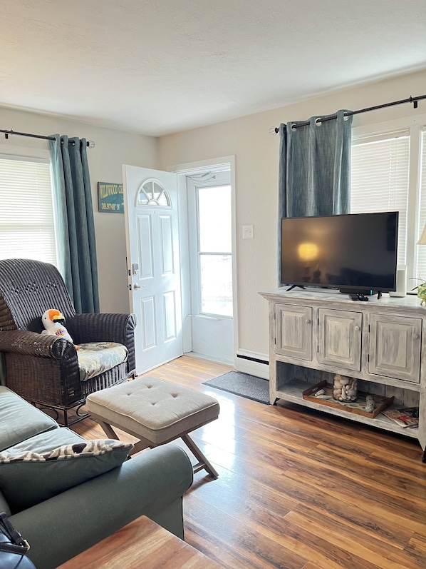 A living room with a sofa, a chair, a television, and a cabinet.
