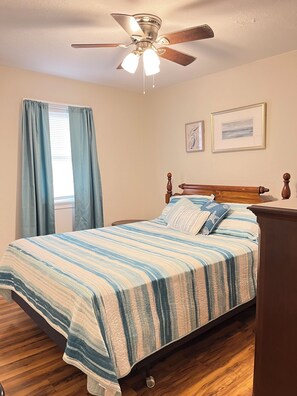 A bedroom with a bed, wooden headboard, ceiling fan, and two framed pictures on the wall. - Conveniently located Wildwood Crest Condo!  Enjoy the Jersey Shore! (Wildwood Crest)