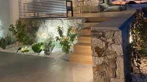 A modern two-story house with a balcony, stone steps, and outdoor seating. - Eliandreia Luxury Villa (Lefkada)