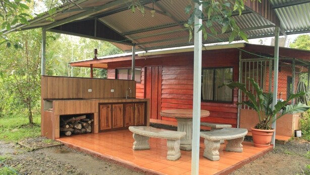 A wooden cabin with a covered patio, outdoor seating, and a fire pit. - Don Beto House (Provincia de Puntarenas)