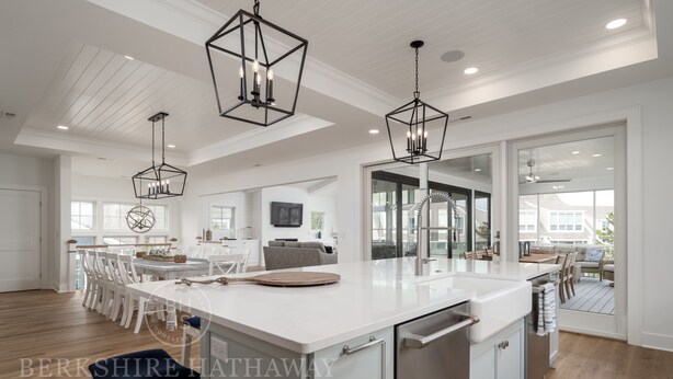 A spacious kitchen with a large island, pendant lighting, and a view to the outdoor patio.