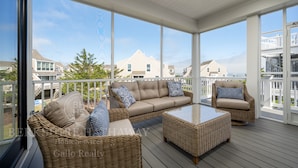A covered outdoor area with wicker furniture, including a sofa and chairs, and a coffee table.