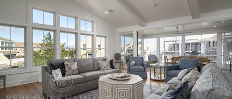 A spacious living room with a high ceiling, large windows, and a modern design.