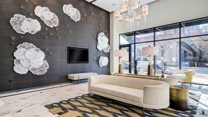 A modern living room with a sofa, a flat-screen TV, decorative wall art, and a chandelier. - The Urban Oasis in Midtown (Atlanta)