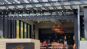 An outdoor seating area with orange chairs and a black sign reading "Vinedo Local." - The Urban Oasis in Midtown (Atlanta)