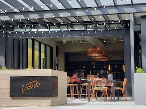 Vinedo restaurant features a contemporary design with a black facade, large windows, and a unique entrance marked by a planter.