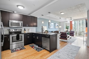 Enjoy a compact kitchen with stainless steel appliances, a dining area with city views, and a cozy seating area with a sofa.