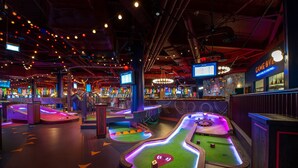 A vibrant arcade with neon-lit pinball machines and a bar area. - The Urban Oasis in Midtown (Atlanta)