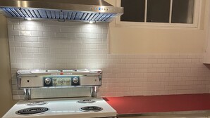 A kitchen with a white stove, a stainless steel range hood, and a window above the sink. - Old Town Treasure - Best location for a 30 day stay! (Fort Collins)