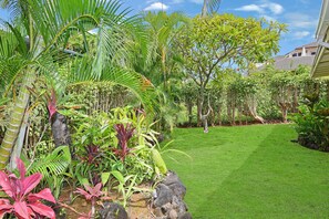 Un rigoglioso giardino con diverse piante tropicali e un prato curato.