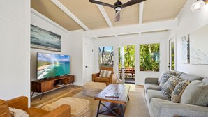 A spacious living room with a television, comfortable seating, and large windows offering a view of the outdoors.