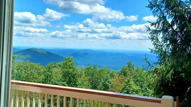 Ein Balkon mit Blick auf eine gebirgige Landschaft und einen klaren Himmel.