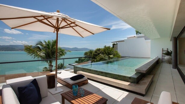 A modern outdoor terrace with a pool, white furniture, and a view of the sea. - Muscat 3-Bedroom Villa with Beach Access (Koh Samui)