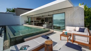 A modern house with a swimming pool, outdoor seating, and a large glass door leading to a living area. - Gamay 3-Bedroom Villa with Beach Access (Koh Samui)