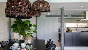 A modern dining area with a dark wooden table, black chairs, and wicker pendant lights. - Gamay 3-Bedroom Villa with Beach Access (Koh Samui)