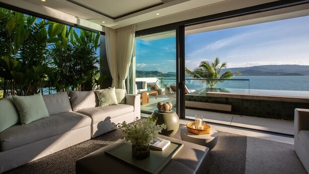 A modern living room with a sofa, coffee table, and a view of the ocean. - Gamay 3-Bedroom Villa with Beach Access (Koh Samui)