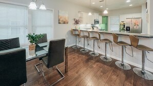 Uma cozinha moderna com armários brancos, uma parede de destaque verde e eletrodomésticos de aço inoxidável.