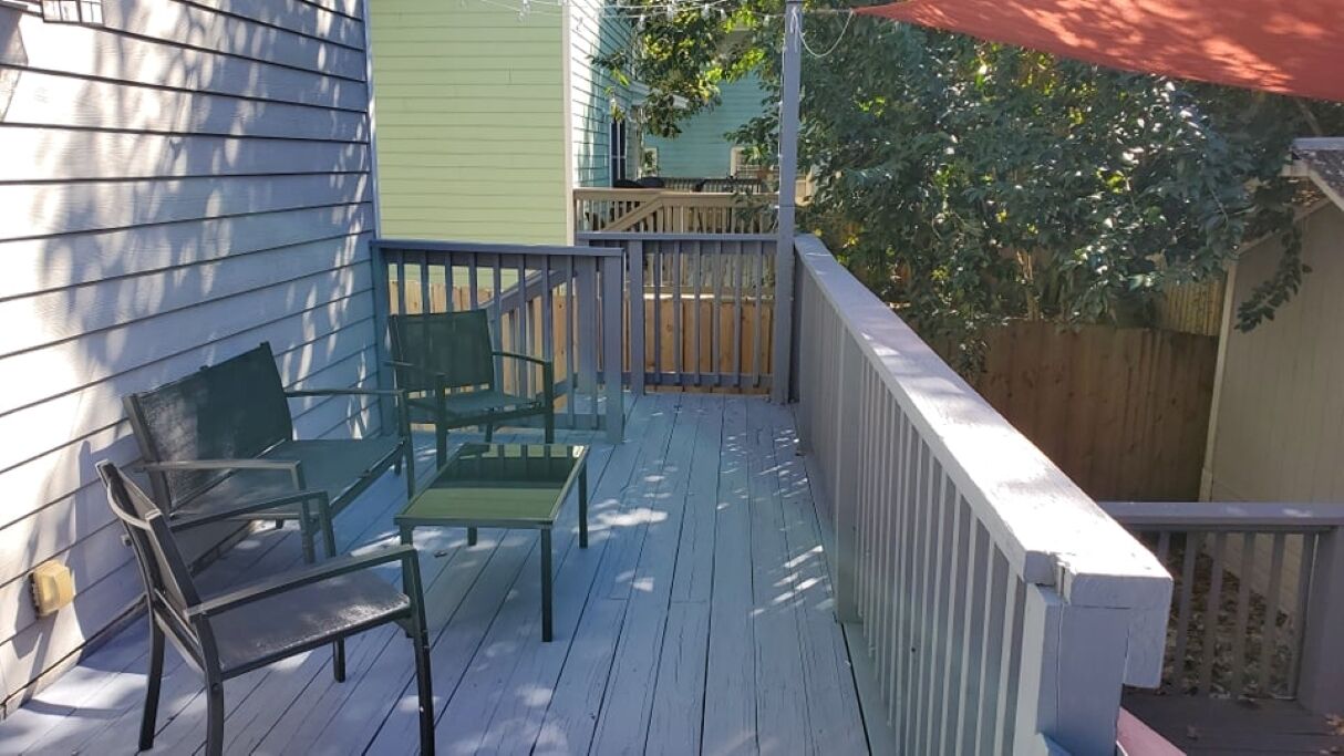 A wooden deck with two green chairs and a table.