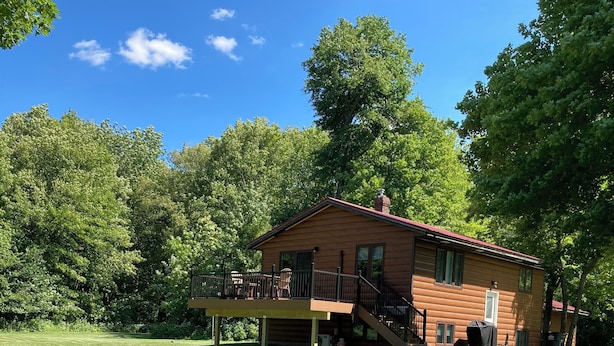 A wooden cabin with a deck and stairs, surrounded by a well-maintained lawn and trees. - Lake Mille Lacs Cabin. Onamia (Onamia)