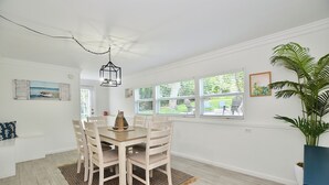 A dining area with a wooden table and chairs, a patterned rug, and a hanging light fixture. - Driftwood Way~ No Checkout Chores (Jensen Beach)
