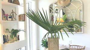 A bright room with a white interior, a large mirror, and a glass table with a woven basket.