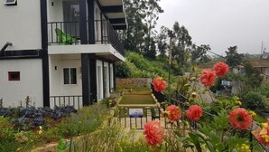 A two-story building with balconies, surrounded by a garden with various plants and flowers. - Hotel Coldworld (Nuwara Eliya)