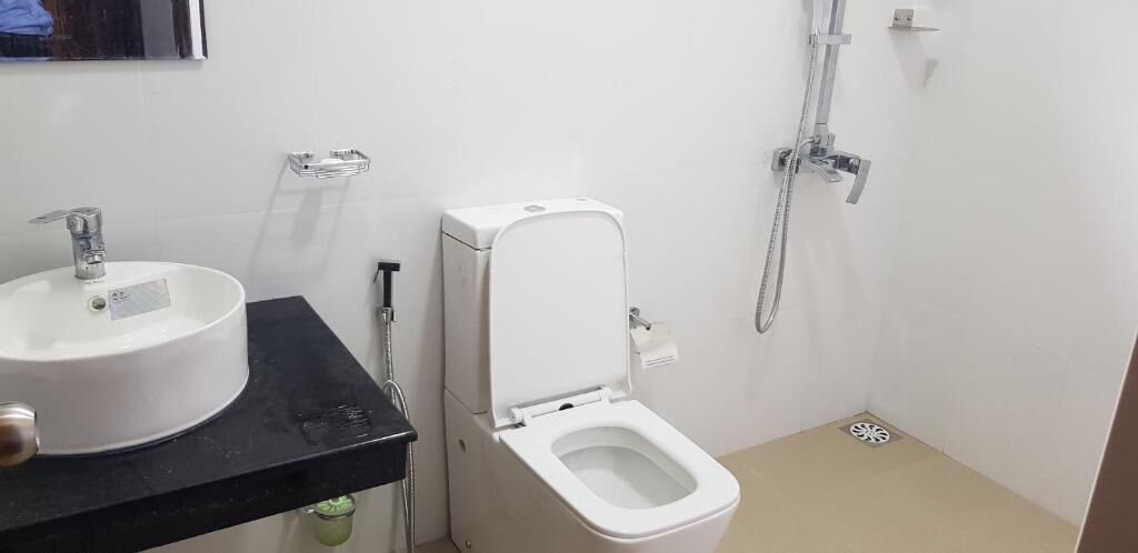 A bathroom with a white sink, toilet, and shower.