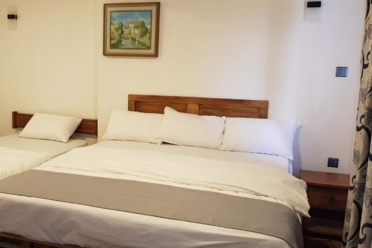 A double bed with a wooden headboard, a bedside table, and a painting on the wall.