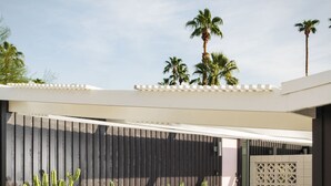 Um pátio moderno ao ar livre com piso de concreto, pedriscos brancos e diversos cactos.