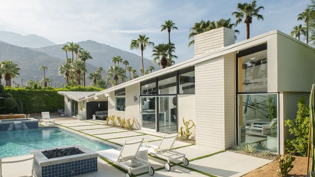 Uma casa moderna com piscina, espreguiçadeiras e vista para montanhas.