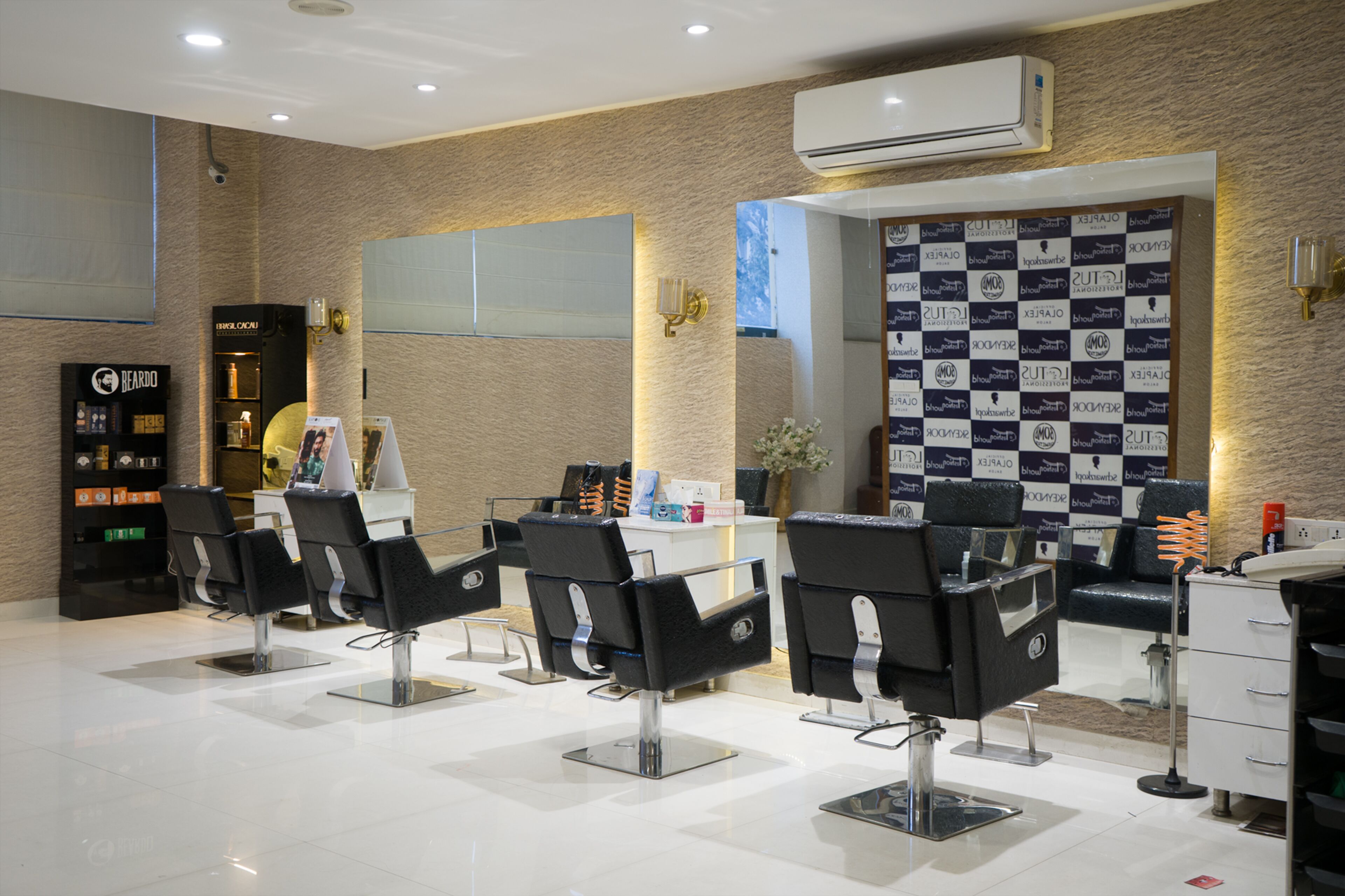 A salon with multiple black salon chairs, a reception desk, and a wall with various brand logos.