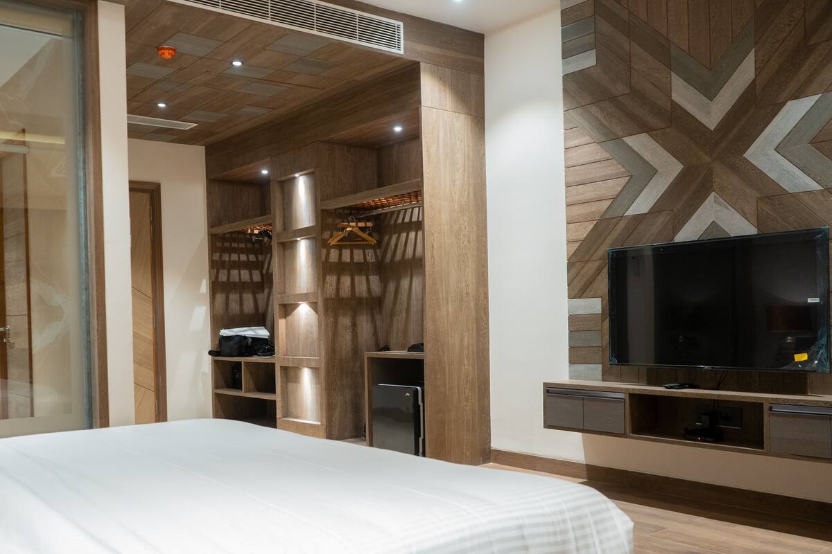 A modern hotel room with a large bed, a TV, and built-in wardrobes.