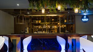 Zona de bar con diseño moderno, que incluye una barra con copas y un letrero que dice 