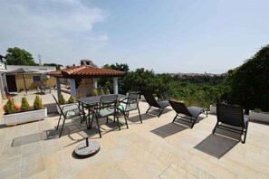 An outdoor patio with a table and chairs, a small gazebo, and a view of the landscape.