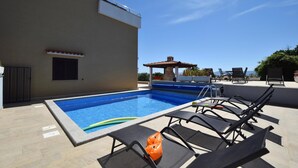 Une piscine sur le toit, dotée de chaises longues, d’un petit espace salon couvert et offrant une vue sur la mer.