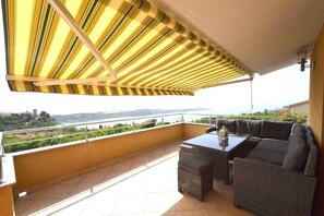 Un balcon donnant sur une étendue d’eau, un canapé et une table.