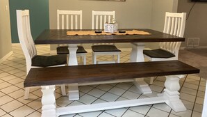 A dining table with white chairs and a dark wooden top.