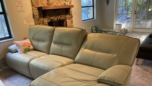 A beige leather sectional sofa with a fireplace in the background.