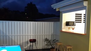 Un patio con piscina, una zona de bar y un área de estar.